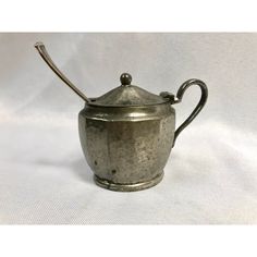 an old silver teapot with a handle on it's side, sitting on a white background