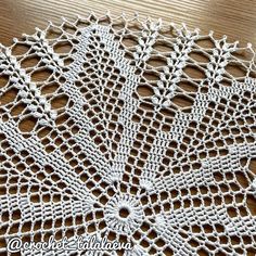 a white doily on top of a wooden table covered in crocheted lace