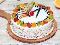 a white cake topped with fruit on top of a wooden cutting board next to an orange slice