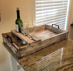 a wine bottle and two glasses on a wooden tray