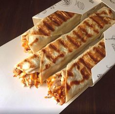 three quesadillas cut in half sitting on top of a paper wrapper