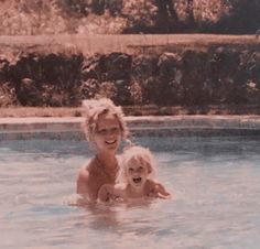 a woman and child are playing in the pool