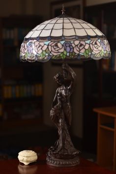 a table lamp sitting on top of a wooden table next to a cup and cookie