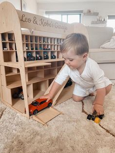 a young boy playing with toy cars on the floor in front of a bookcase