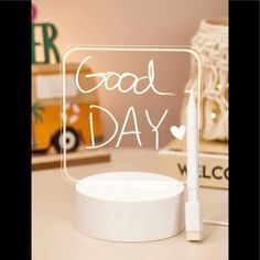 a white light up sign with the words good day written on it next to a pen