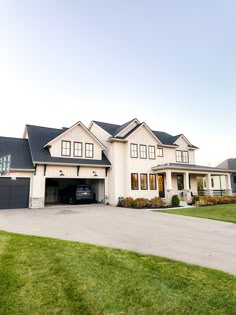 a large white house with a car parked in the driveway and two garages on each side