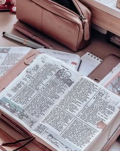 an open bible sitting on top of a desk next to a pen and pencil holder