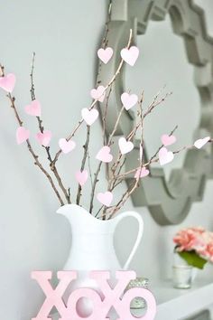 a vase filled with pink hearts sitting on top of a white shelf next to a mirror