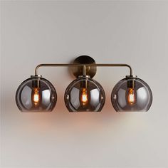 three lights that are on the side of a wall mounted fixture in an industrial style