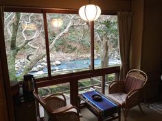 a living room filled with furniture and a large window overlooking a river in the distance