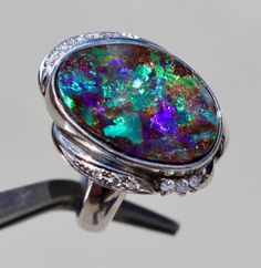 Metal: Platinum, marked "Pt900," Tested Platinum 900 Central stone: Genuine Boulder Opal 25.1 x 12.5 x ~5-6 mm (uneven surface), Oval Cabochon, reflects magnificent colors, Outstanding quality, no damages, 11.05cts (stamped inside for opal weight "11.05")  Side Stones : Genuine Diamond, 0.14cts round cuts, stamped inside "0.14" by maker signifying diamond weight, G-H, SI2-I1 Ring Size : about 6 (sizable)  Setting: ~0.98" along a finger Gross Weight : 18.22 g / 0.64 oz Condition: Excellent vintage, Light Normal polishable wear on platinum  txzj pxzj3215 txzj-11 txzj101 txzj115 Boulder Opal Ring, Australian Boulder Opal, Opal Ring, Boulder Opal, Oval Cabochon, Opal Rings, Rings Statement, Beautiful Rings, Statement Rings