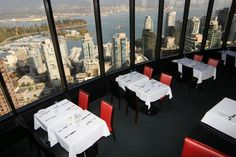 a dining room with tables and chairs overlooking the cityscape in vancouver, canada