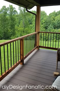 a porch with wooden railings and chairs on the outside deck overlooking a grassy field