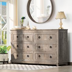 a dresser with drawers and a round mirror on the wall above it in a living room