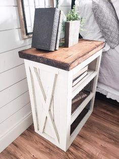 a small white table with some plants on it and a mirror in the corner next to it