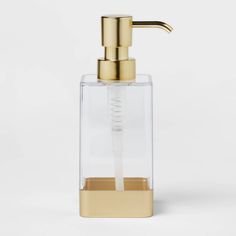 a soap dispenser with a gold faucet and clear glass container