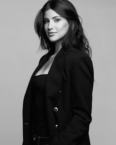 a woman is posing for a black and white photo with her hands in her pockets