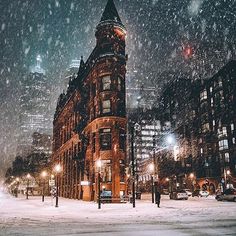 a snowy night in new york city with the lights on and snow falling all around