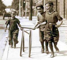 an old photo of two young boys playing on the sidewalk with a crutch