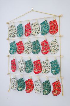 several stockings hanging on a clothes line with pegs attached to the wall, all decorated in different colors and patterns