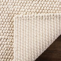 a white rug on top of a wooden floor next to a brown and white rug