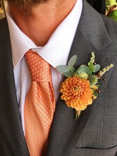 a man wearing an orange tie and flower boutonniere on his lapel