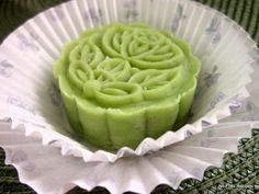 a green cake sitting on top of a white paper cupcake liner in a bowl