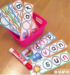 a pink container filled with lots of different colored letters and numbers on top of a wooden table