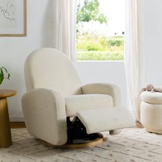 a living room with a rocking chair and footstool in front of a window