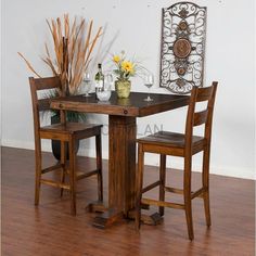 a wooden table with two chairs and a vase filled with flowers on top of it