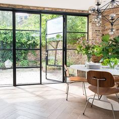 a dining room table and chairs with glass doors leading to an outdoor area that looks out onto the garden