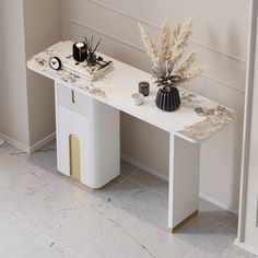 a white table with two vases on top of it next to a plant and other items