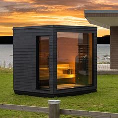 a small house sitting on top of a lush green field next to a body of water