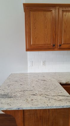 an empty kitchen with wooden cabinets and marble counter tops