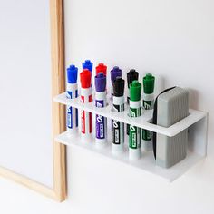 several different colored markers on a white shelf