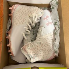 a pair of white and pink tennis shoes in a box next to a green pen