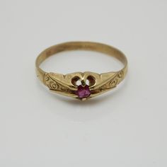 a gold ring with a pink stone in the middle and two hearts on it's side