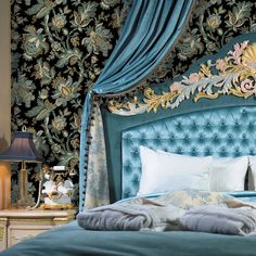 a bed with blue velvet headboard and pillows on it, next to a lamp