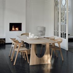 a dining room table with chairs around it and a fireplace in the wall behind it