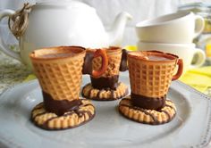 three ice cream cones are on a plate next to a teapot and saucer