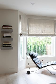 a chair sitting in front of a window next to a book shelf