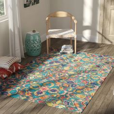 a brightly colored area rug in the corner of a room with a chair and window