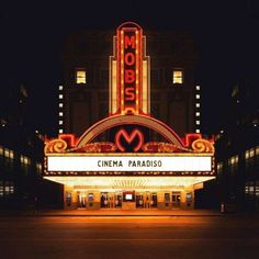 a theater marquee lit up at night with the word cinema paradis written on it