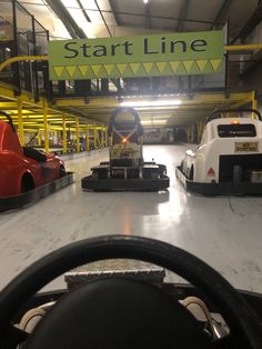 the inside of a car garage with two cars parked in front of it and a sign that says start line