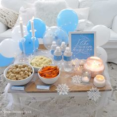 a table topped with food and candles on top of a wooden table covered in snowflakes