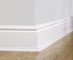 the corner of an empty room with wood flooring and white paint on the walls