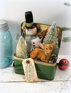 a small suitcase filled with stuffed animals next to a christmas ornament on a table