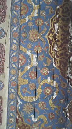 closeup of an ornately designed blue and gold wallpaper with red, white, yellow, and blue colors