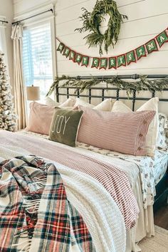 a bedroom decorated for christmas with plaid bedding and wreaths on the headboard