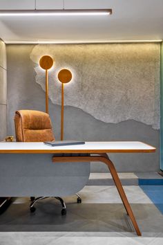 an office with a desk, chair and lamp on the wall in front of it